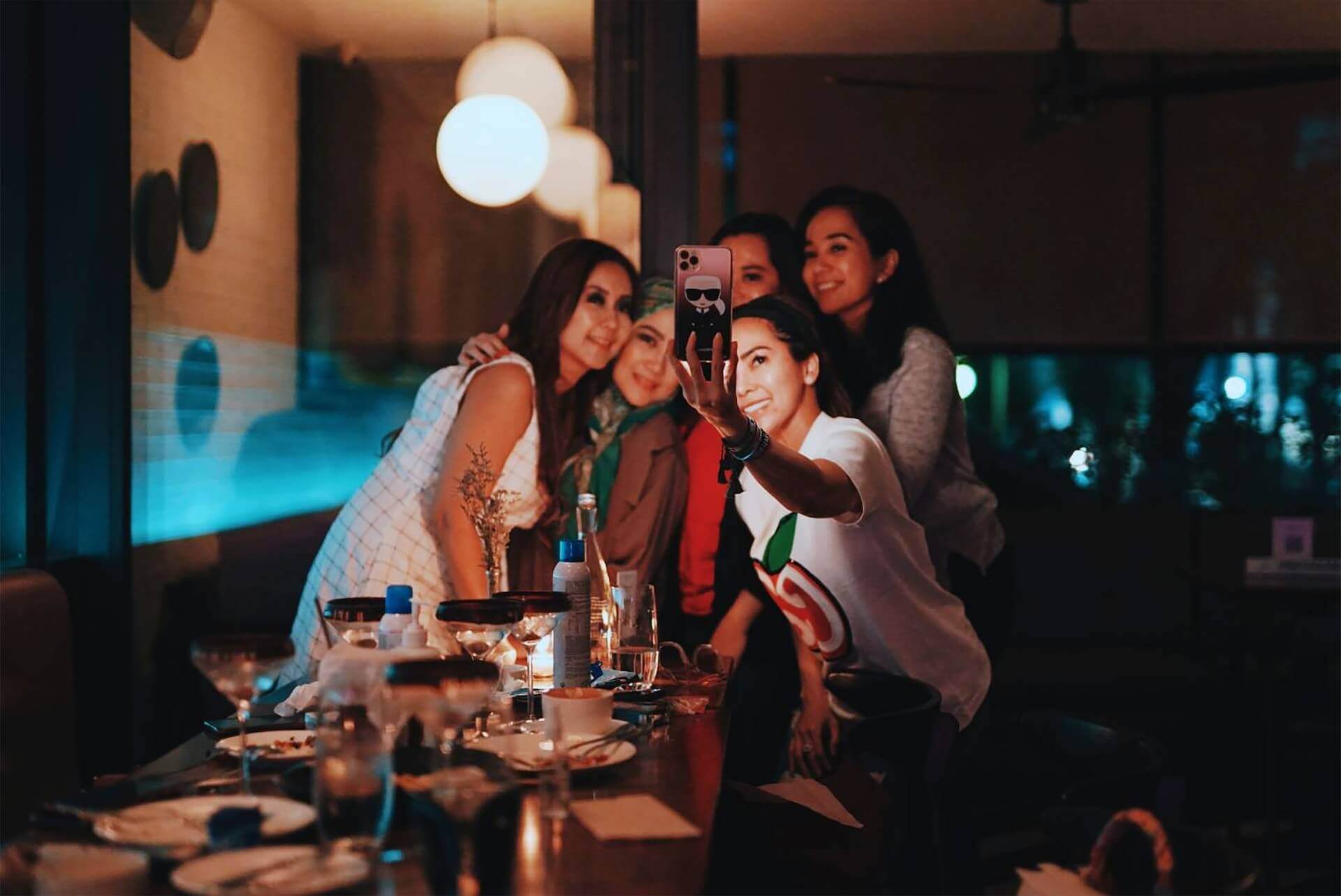 Women gather to take selfie at dinner party.