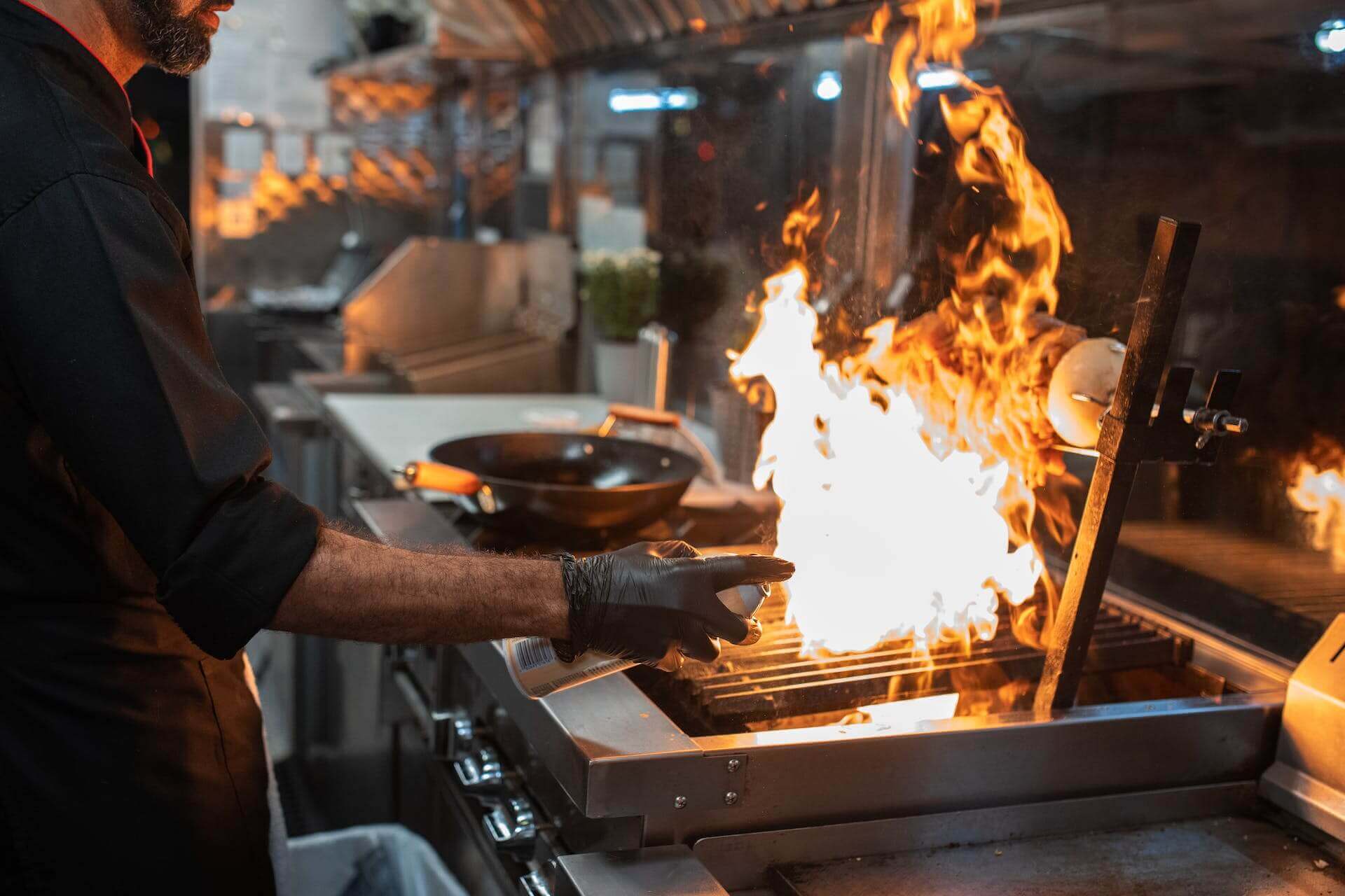 Chef working cooking on a flaming grill